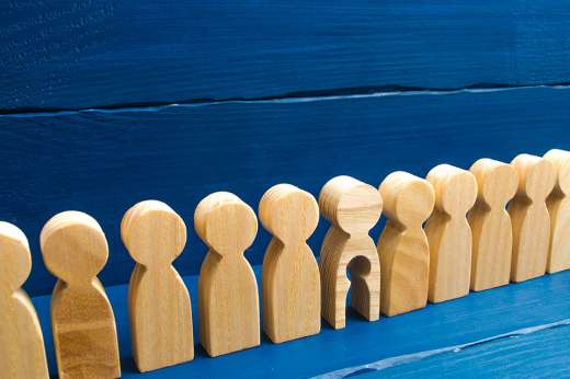 Foto: Holzfiguren in einer Reihe, eine hat ein ausgeschnittenes Kind